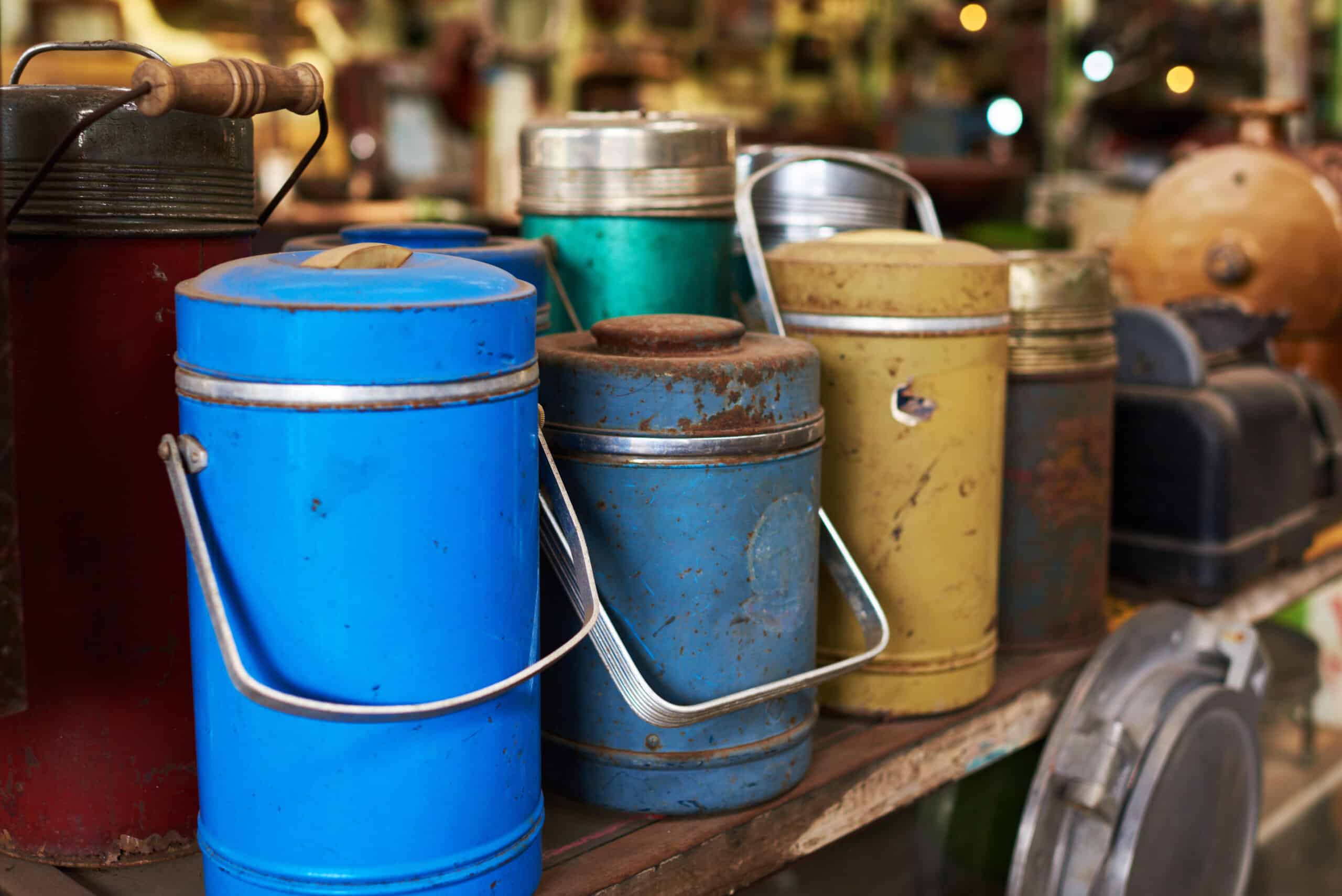 Many used thermos bottle. Retro equipment. Various objects for sale at a indoor flea market. View of a display full of interesting old things for sale. Vintage assorted second-hand objects. Old thermos flasks